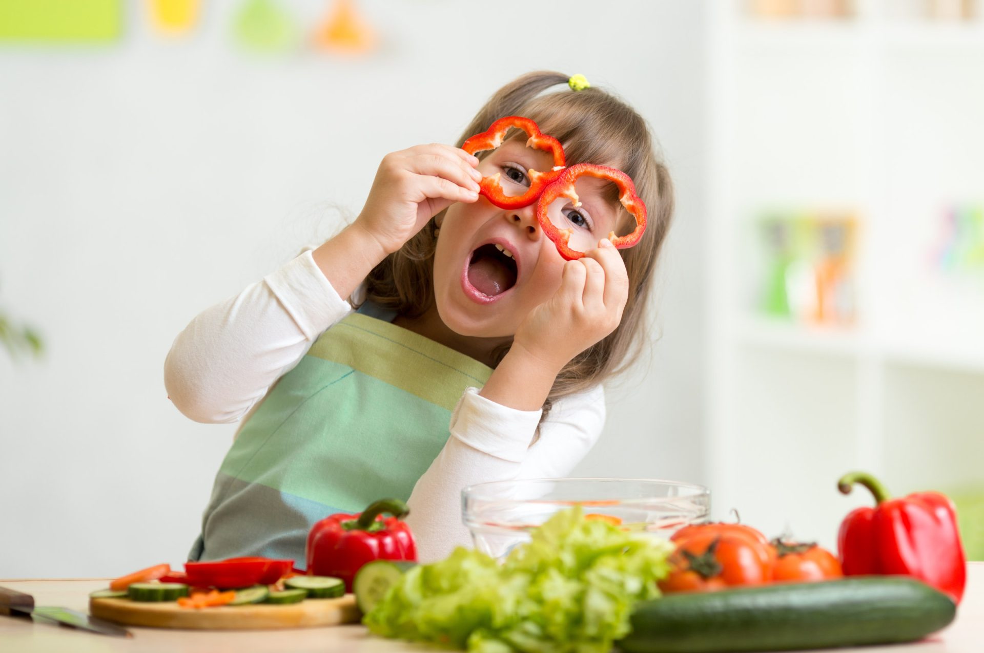 kid girl having fun with food vegetables at kitchen